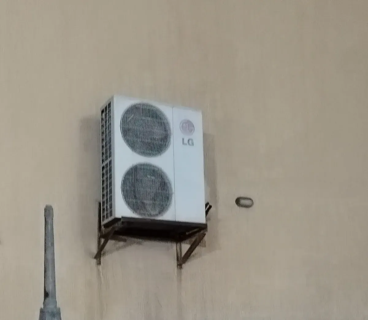 وحدة سبليت خارجية بمروحتين مثبتة على حامل جداري.